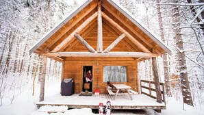 A wooden cabin with a pitched roof, a wooden deck, and a bench. - Chalets Huttopia White Mountains (Conway)