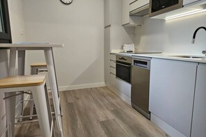 A modern kitchen with white cabinets, a stainless steel dishwasher, and a microwave.