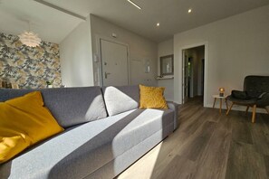 A modern living room with a grey sofa, a small side table, and a chair.