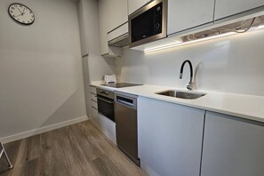 A modern kitchen with white cabinets, stainless steel appliances, a microwave, and a dishwasher.
