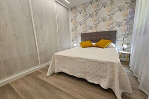 A bedroom with a bed, a nightstand, a lamp, and a window.