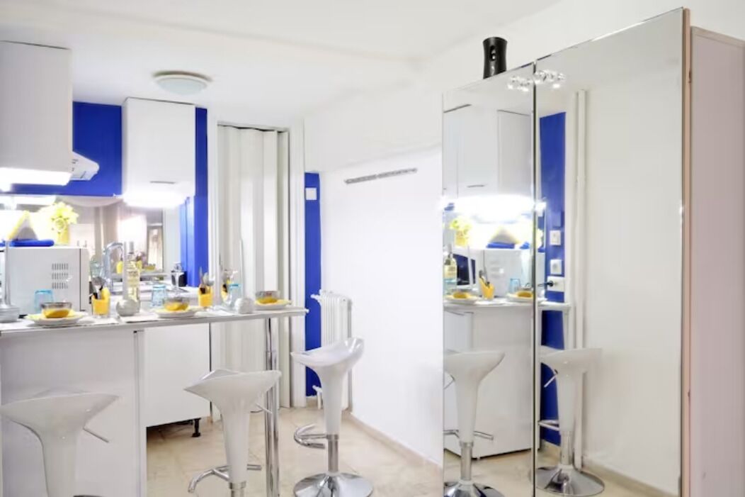 A modern bathroom with a large mirror, white vanity, and two bar stools.