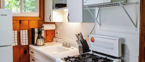 A compact kitchen with a stove, sink, and microwave.