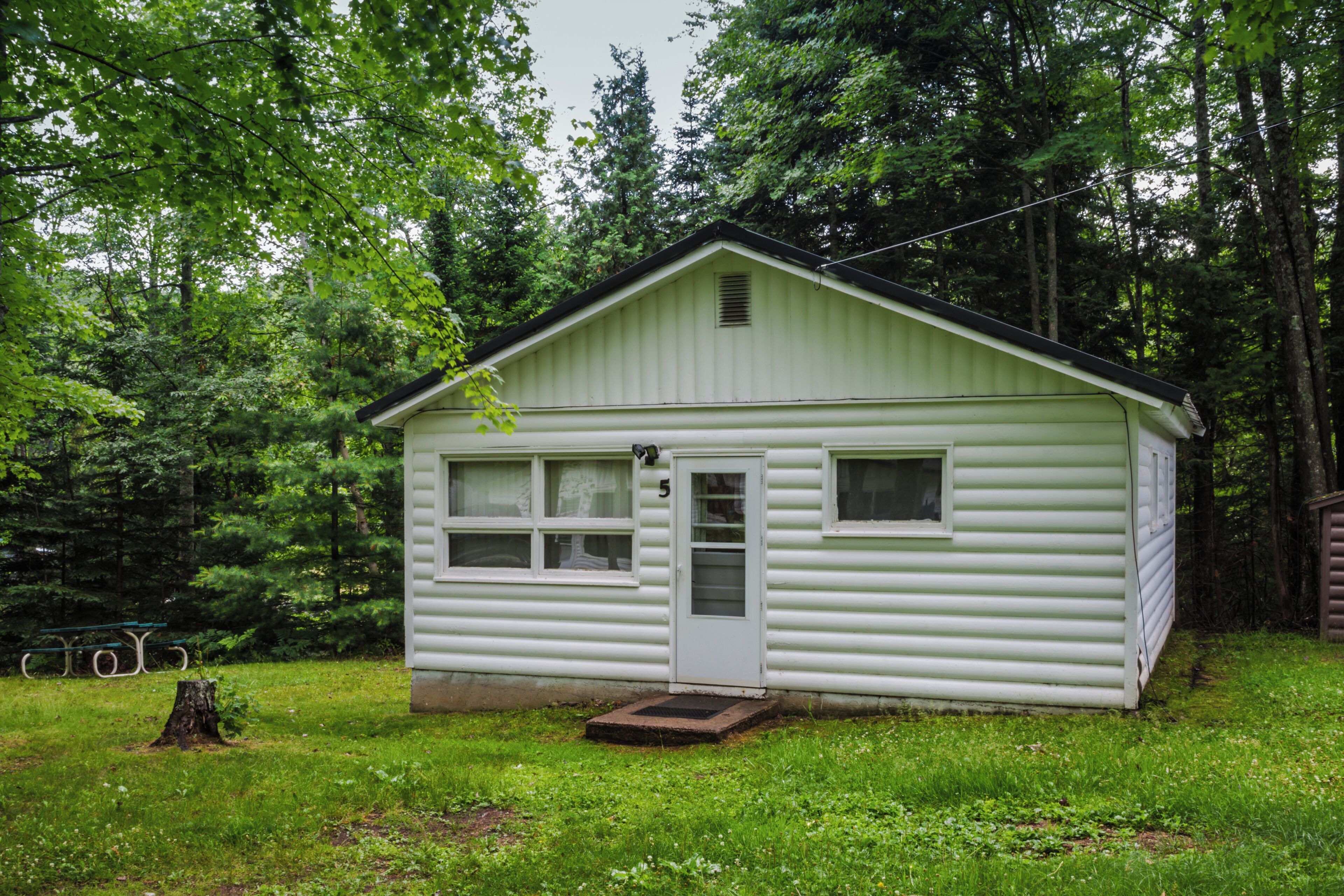 A small, single-story cabin with a front door, windows, and a small porch.