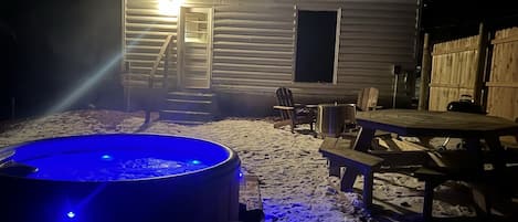 Uma cabana com hidromassagem, deck de madeira e um espaço de varanda coberto.