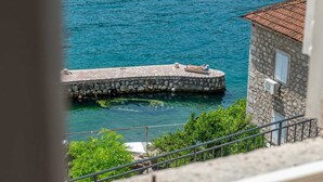 A stone pier extending into a clear blue sea, with a small building on the right.