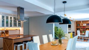 A modern kitchen with a central island, white chairs, and pendant lighting.