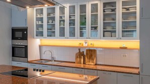 A modern kitchen with built-in appliances, a granite countertop, and a glass-fronted cabinet above the sink.