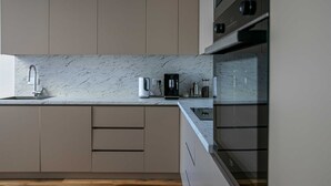 A modern kitchen with marble countertops, stainless steel appliances, and wooden flooring. - Villa Beta with Pool (Budva)