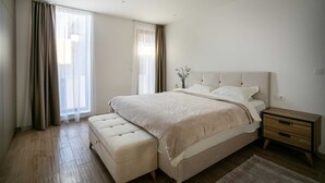 A modern bedroom with a large bed, a nightstand, and a bench. - Villa Gama with Pool (Unknown)