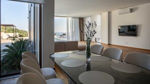 A modern dining area with a large table, chairs, and a vase of flowers. - Villa Gama with Pool (Unknown)