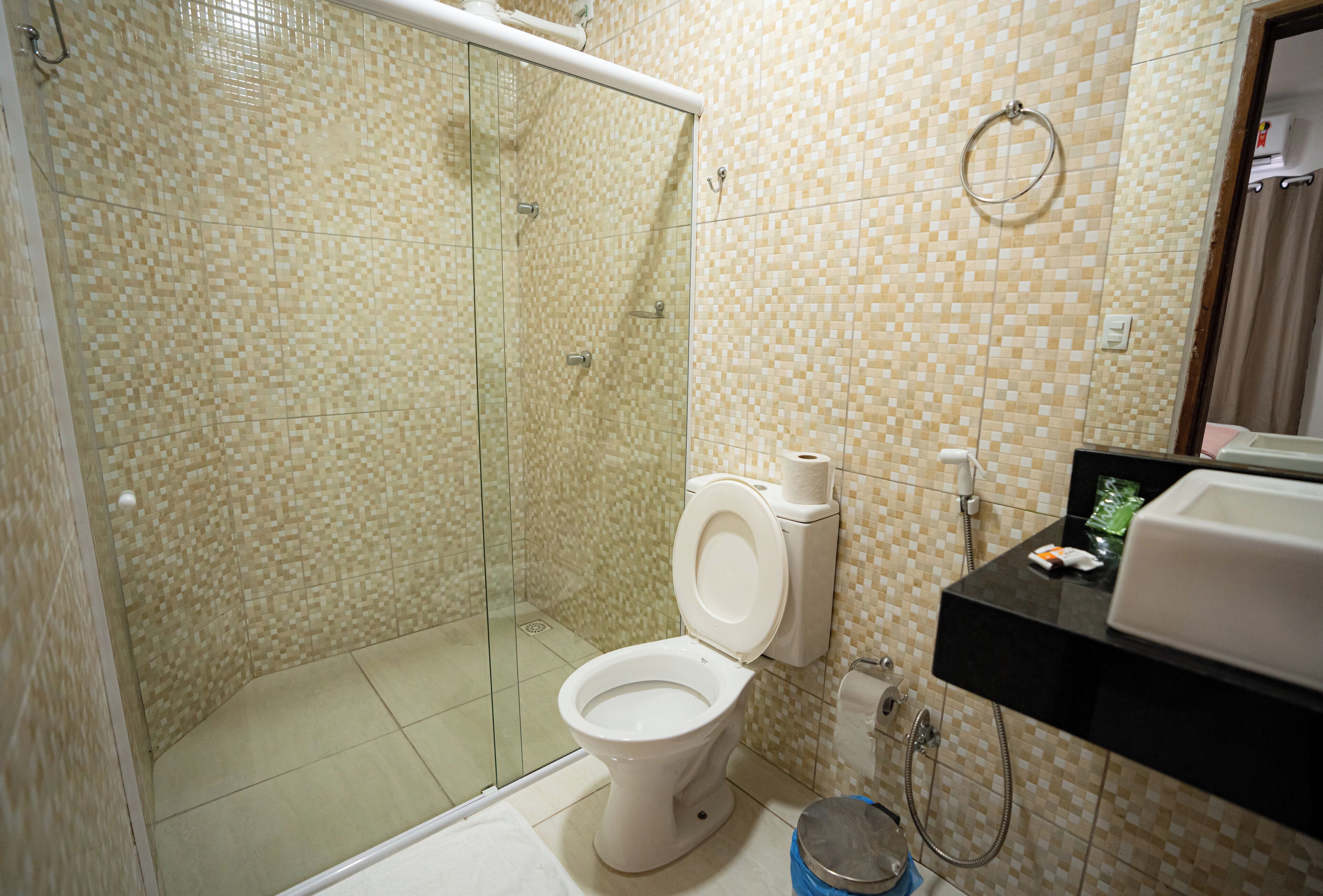 A bathroom with a glass-enclosed shower, a toilet, and a sink.