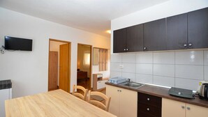 A compact kitchen with a wooden table, dark cabinets, and a tiled backsplash.