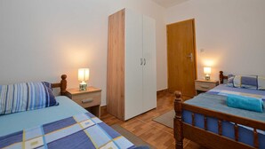 A bedroom with two beds, a wardrobe, and a door.