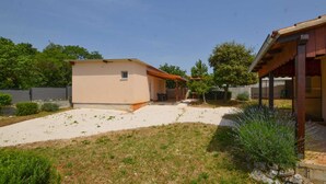 A single-story house with a small attached garage, a covered patio, and a well-maintained lawn.