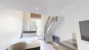 Un dormitorio moderno con cama, una silla, un televisor y una escalera.