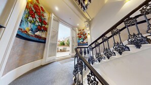 Una escalera con barandillas negras ornamentales y murales florales en las paredes.