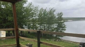 Eine Holzterrasse mit Blick auf einen See und Bäume.