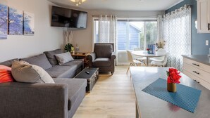 A modern living room with a sofa, armchair, and a dining table with chairs. - Blue Octopus #6 Beach Access. Ground Level. (Rockaway Beach)