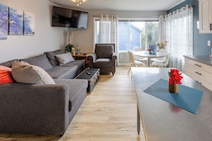 A modern living room with a sofa, armchair, and a dining table with chairs.