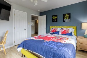 A bedroom with a bed, a chair, a nightstand, and a lamp. - Blue Octopus #6 Beach Access. Ground Level. (Rockaway Beach)