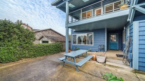 A two-story house with a balcony, a front door, and a picnic table in the yard. - Blue Octopus #6 Beach Access. Ground Level. (Rockaway Beach)