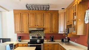 Una cocina con armarios de madera, un lavamanos de acero inoxidable y una cafetera.
