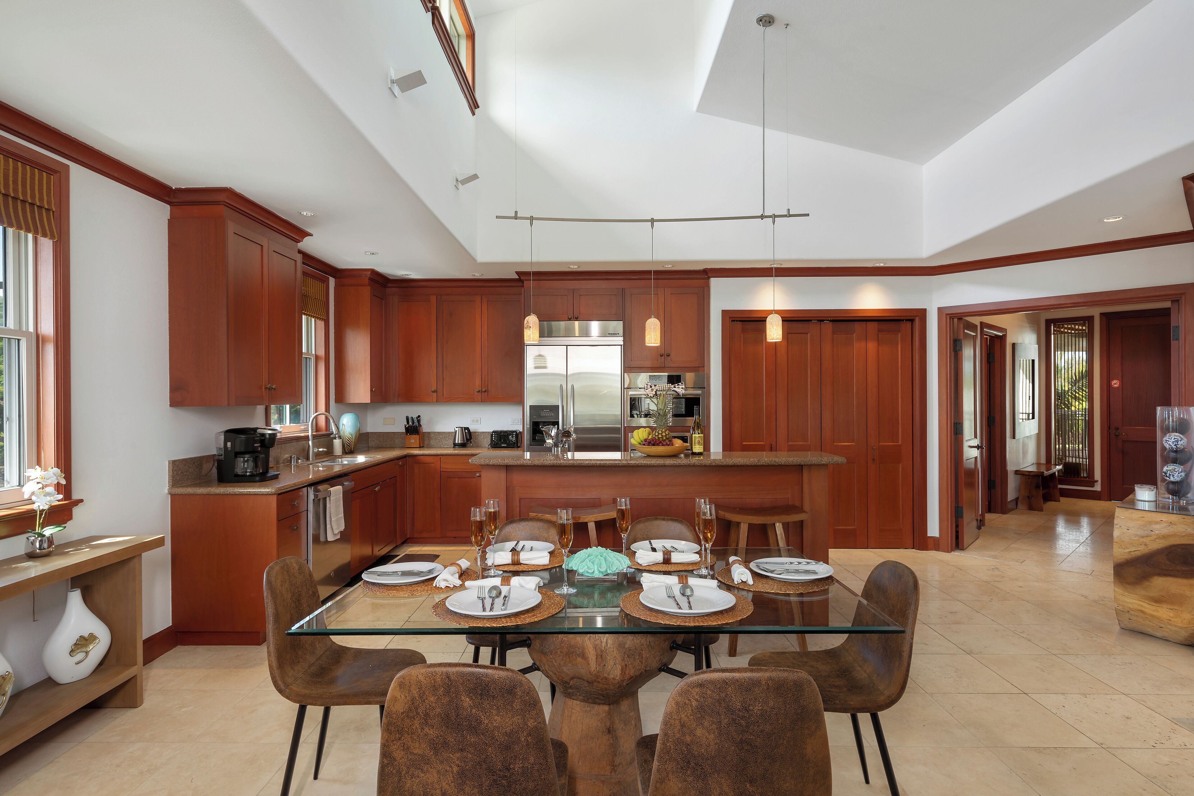 Una cocina moderna con armarios de madera, una mesa de comedor de vidrio y una isla central.