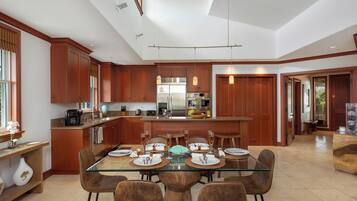 Una cocina moderna con armarios de madera, una mesa de comedor de vidrio y una isla central.
