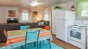 Un espace de vie compact comprenant un canapé, une table à manger avec des chaises, un réfrigérateur, une cuisinière et un téléviseur.