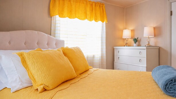 Une chambre d’hôtel avec un lit, une table de chevet, une lampe et une fenêtre avec des rideaux.