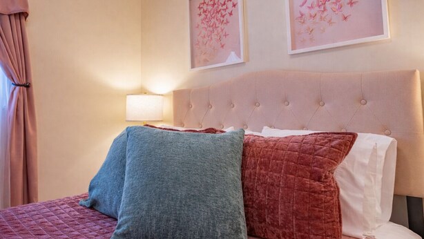 A bed with a tufted headboard, two pillows, and a quilted bedspread. - Lake Front Oasis: 3 Bed 2 Ba Cottage on Lake Logan (Logan)