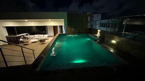A swimming pool with a sunken seating area and a bar.