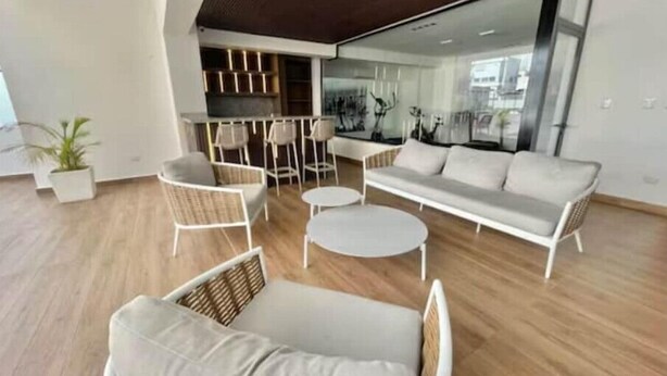 A modern living room with a sofa, two armchairs, a coffee table, and a dining area with chairs and a table.