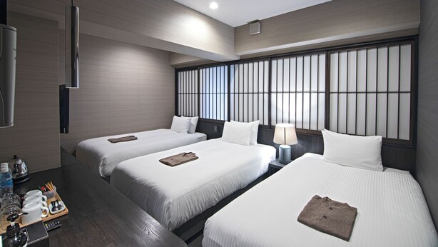 A hotel room with three beds, a minibar, a TV, and a large window with blinds. - HOTEL NINJA BLACK (Kyoto)