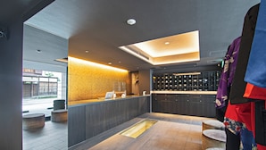 A modern reception area with a central desk, seating, and a view of the outside. - HOTEL NINJA BLACK (Kyoto)
