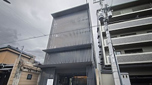A modern hotel entrance with a vertical striped facade, a covered entrance area, and a visible parking garage. - HOTEL NINJA BLACK (Kyoto)