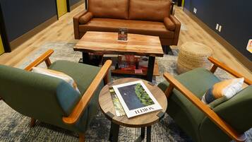 Ein stilvoller Loungebereich mit einem braunen Ledersofa, grünen Sessel und einem Holztisch.