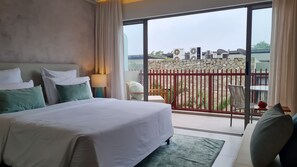 Une chambre d’hôtel comprenant un lit, une table de chevet, une lampe, une vue sur le balcon extérieur et un coin repas.