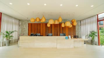 A reception desk with a stone wall backdrop, multiple computer monitors, and hanging wicker lamps.