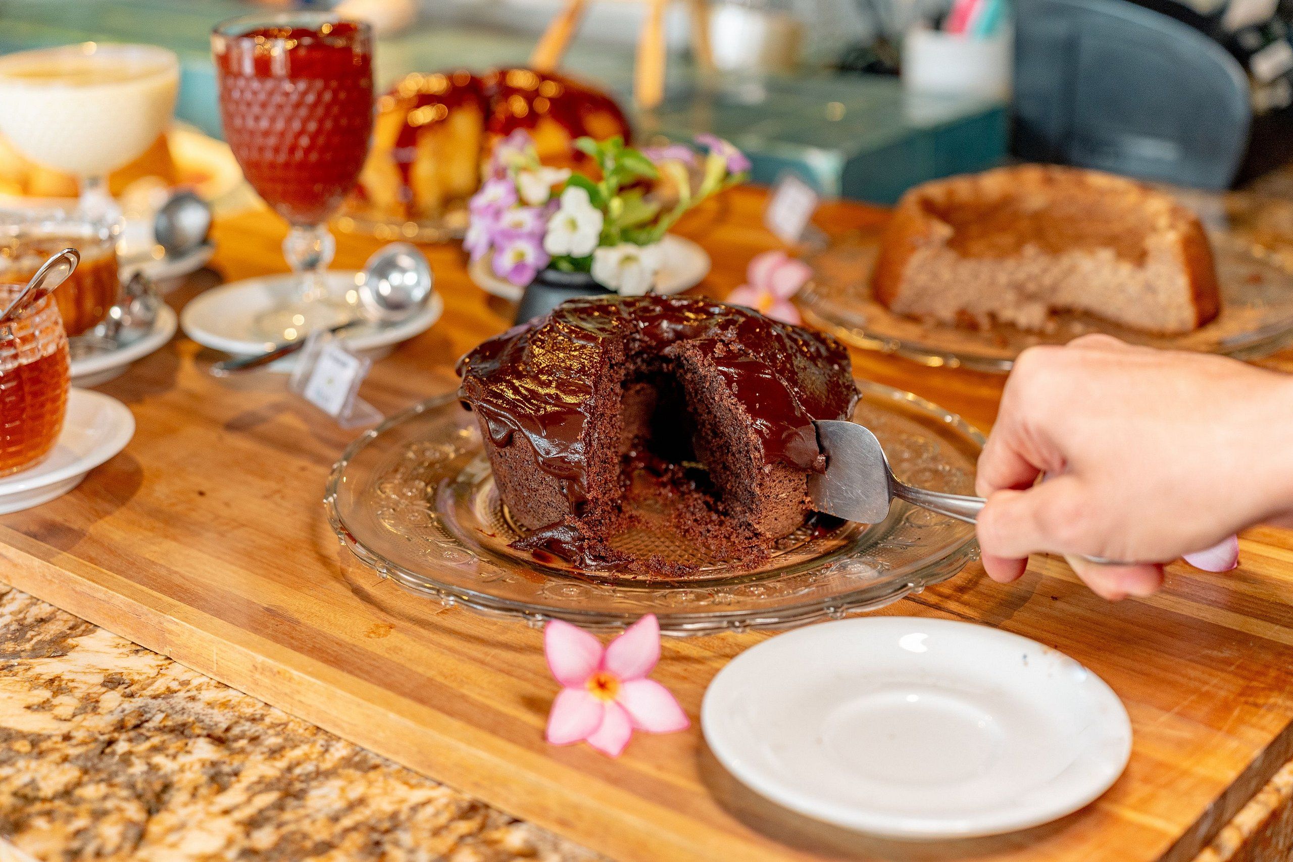 A dessert plate with a chocolate cake, a glass of red beverage, and a slice of bread on a wooden table.