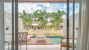 Un balcón con piscina, sillones de descanso y palmeras.