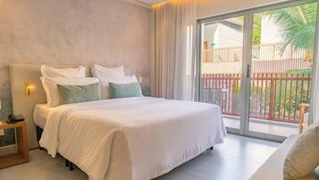 A hotel room with a large bed, a bedside table with a phone, and a view of a balcony with a railing.