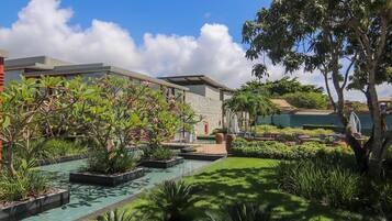 A modern hotel with a swimming pool, lush greenery, and outdoor seating areas.