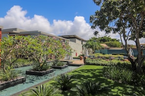 Un hotel moderno con piscina, abundante vegetación y zonas de estar al aire libre.