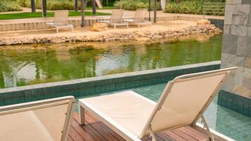 A poolside area with lounge chairs and a small pond.