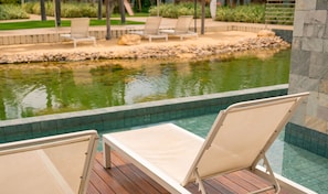 Zona de piscina con sillas de descanso y un pequeño estanque.