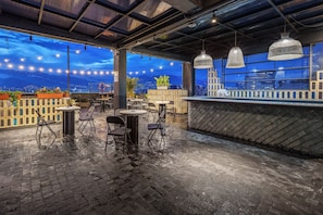 An outdoor seating area with tables and chairs, a bar counter, and a view of the cityscape. - Hotel Zelva Negra (Medellín)