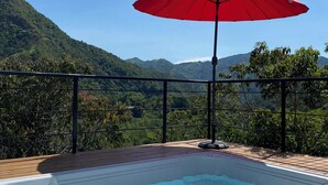 A hot tub with a wooden deck and a red umbrella, surrounded by a metal railing, overlooking a mountainous landscape. - Amari:cabaña Garzas, di Vega Cundinamarca. Balcón,terraza,jacuzzi (La Vega)