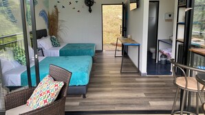A modern room with a bed, a wicker chair, a small table, and a balcony with a view. - Amari:cabaña Garzas, di Vega Cundinamarca. Balcón,terraza,jacuzzi (La Vega)